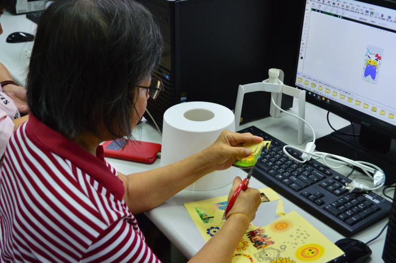 學員正在將設計並列印出來的圖片，剪下貼上燈罩