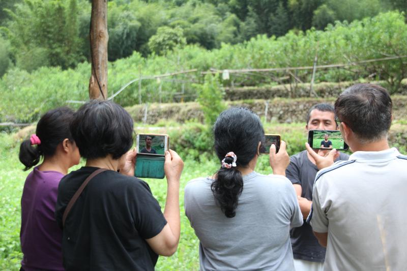 學員圍坐傳統竹屋，以手機拍攝影片記錄mama泰雅古調傳唱。