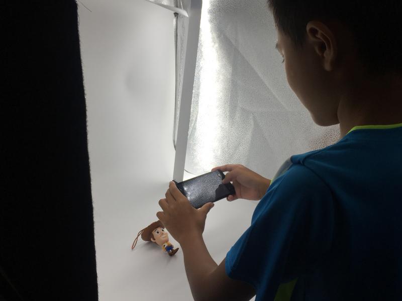 學員對著小型攝影棚使用手機拍下商品/公仔。