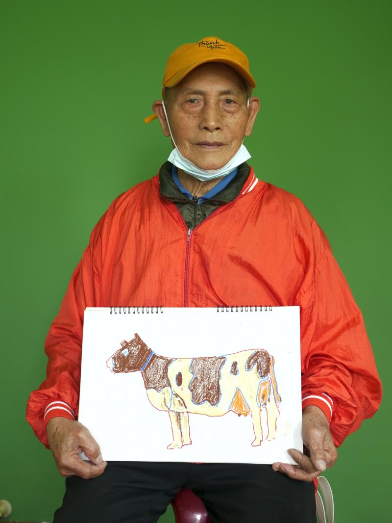 圖中的阿公畫了一頭乳牛，看來阿公對於自己的畫作非常滿意呢！