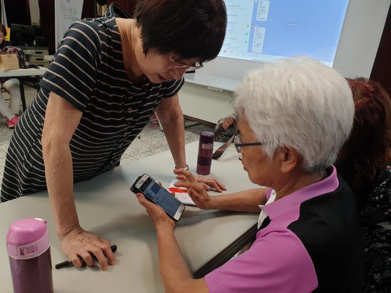 一位中年女性教導高齡女性操作手機