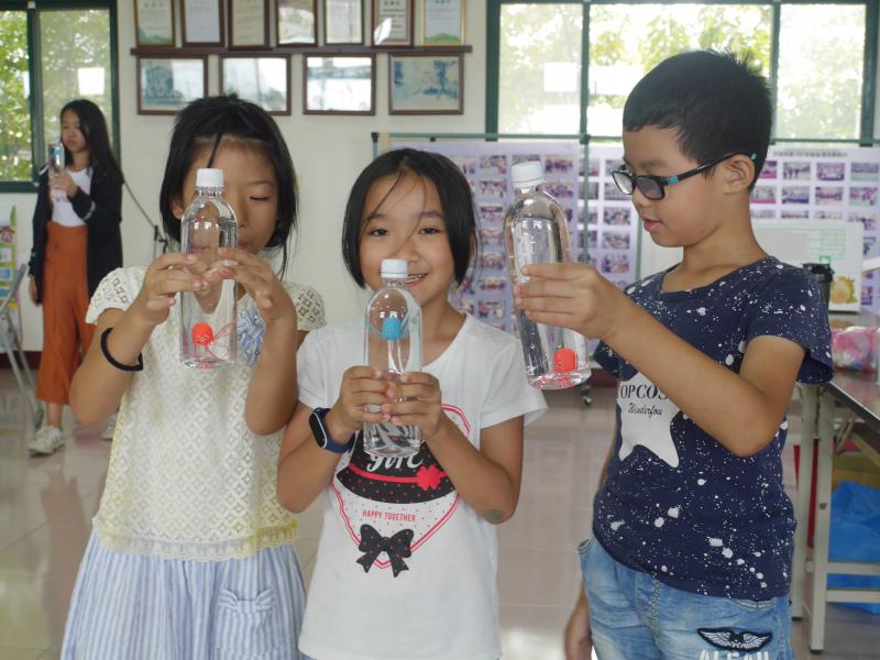 三位小朋友手持水瓶一起玩浮沉章魚