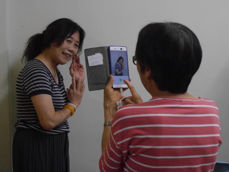 一位女學員用手機拍攝另一位擺拍的學員