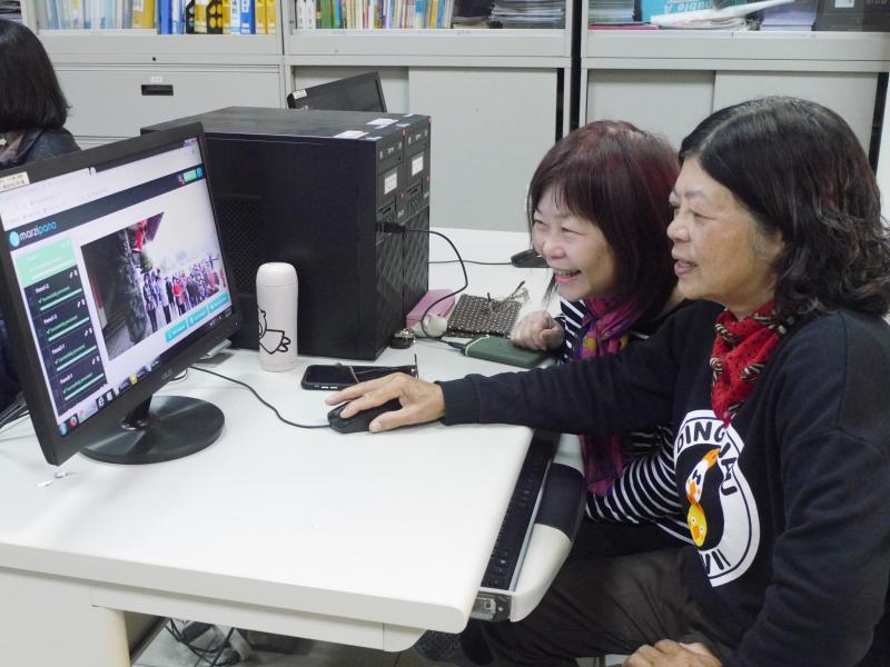 兩位女學員笑著操作電腦上的編輯平台