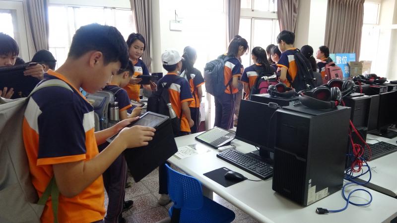 中峰國小陳明達校長與本次課程講師陳萬育正在發放平板電腦給六甲畢業班同學。