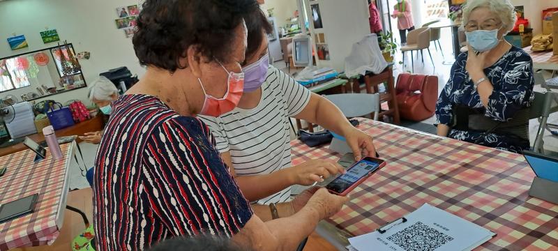 長輩練習著掃描疾管家QR  CODE