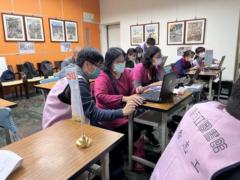 義守大學志工，在旁指導學員操作電腦。