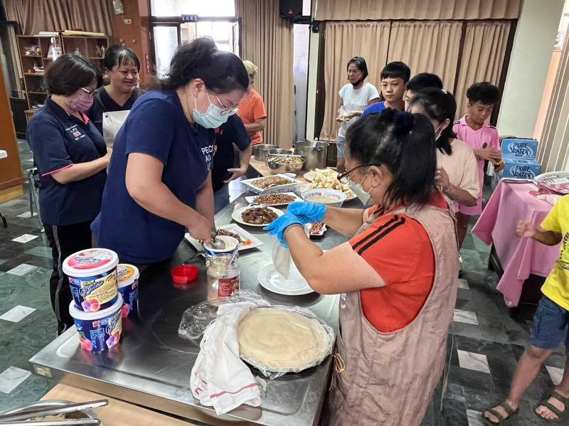 四健會的志工們開始指導親子們做起花生料理。