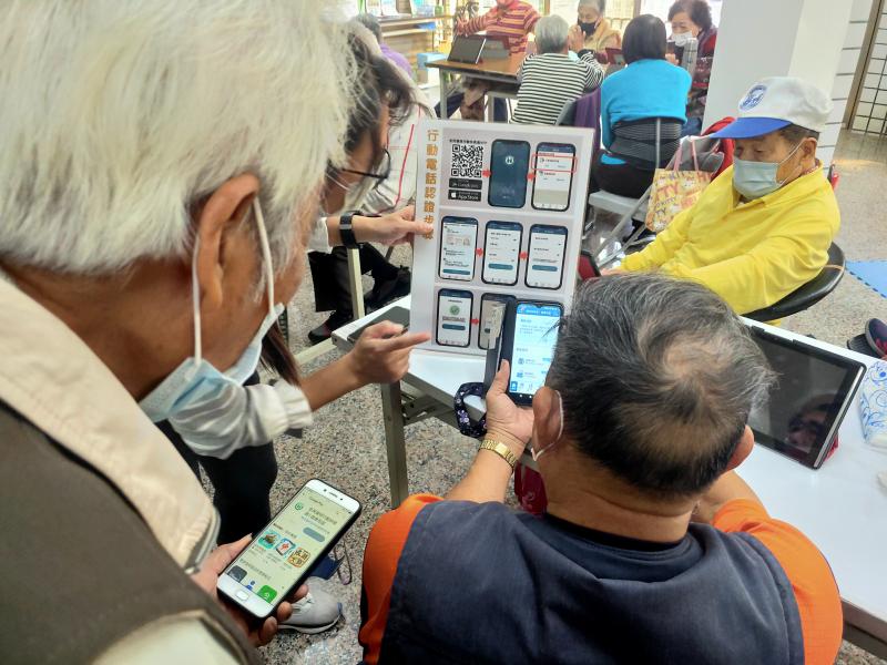長輩用自己手機看著看板上的步驟操作