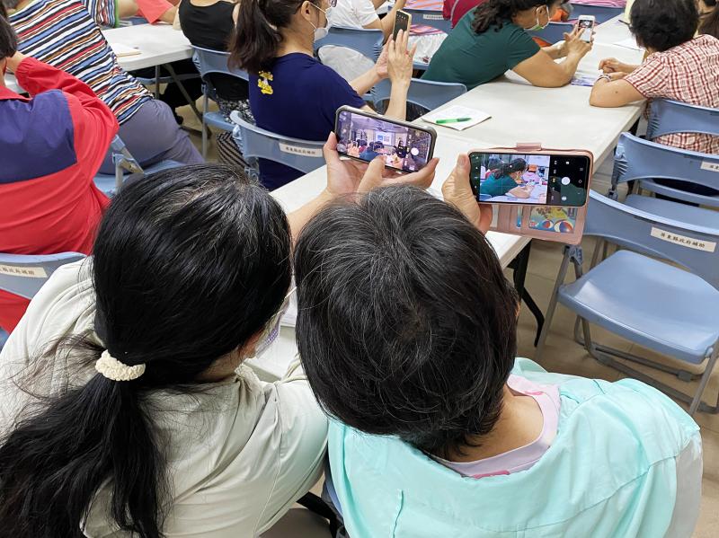 兩位學員開啟手機的相機，認真練習功能應用