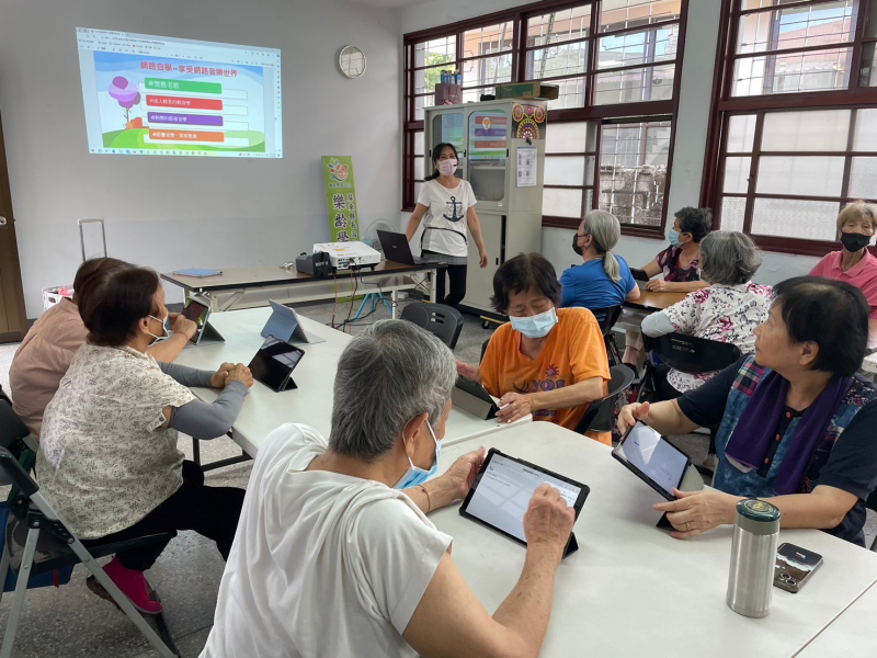 圖中教學員使用手機來上網聽音樂，讓他們可以學會上網