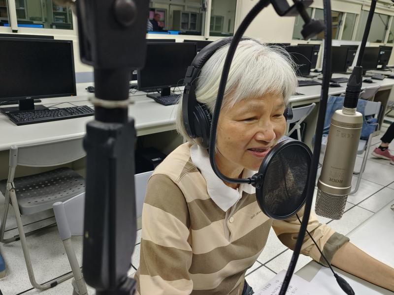 學員戴著耳機在麥克風前，全心投入在節目表演中。