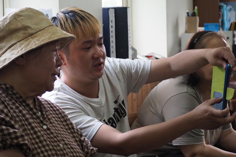 一名青年在教導婦女手機拍攝技巧