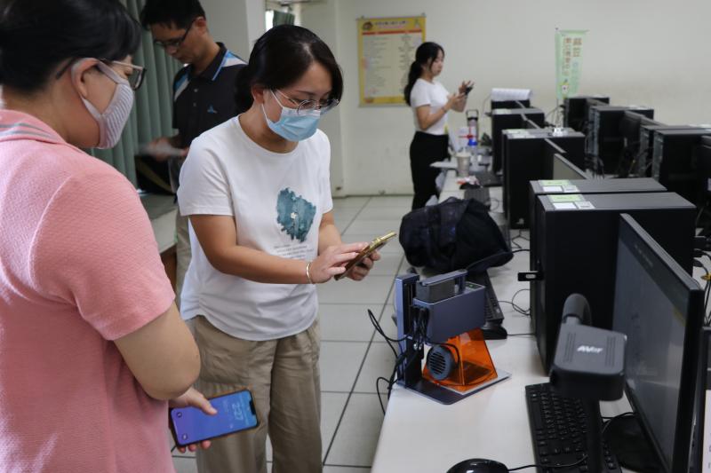 雷雕機進行實際雕刻，學員很認真的用手機紀錄下雕刻的過程。