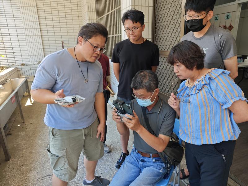 戶外試飛環節讓學員們在騎樓間輪流操作空拍機於廣場上起飛降落，並引導學員將DOC周遭環境做拍攝