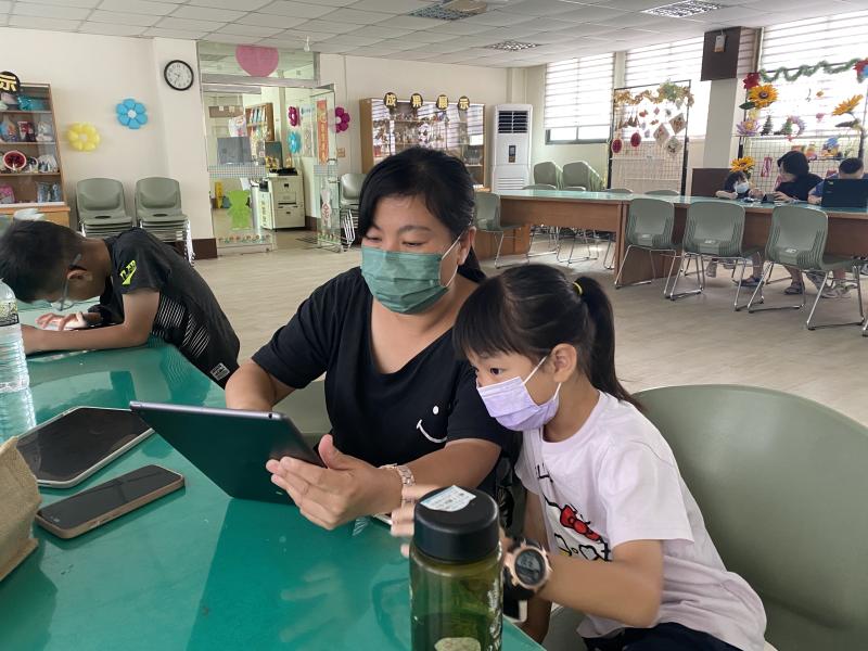 家長陪伴小朋友操作平板，進行名片設計。