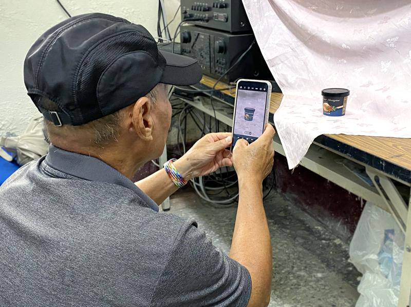 學員使用手機專心拍攝里港社區的商品，作為後續影像合成的練習素材。