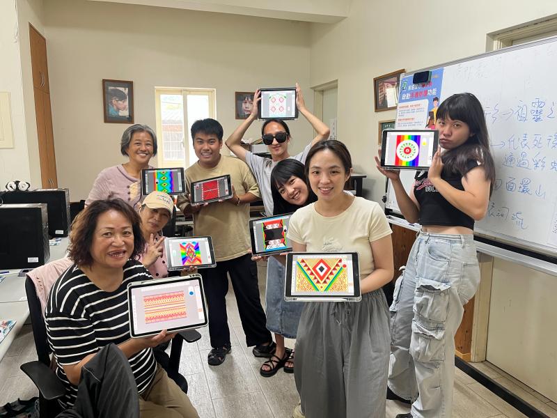 學員們手裡拿著親手完成的泰雅圖紋布料設計作品，臉上帶著笑容站在一起合影，記錄下滿滿成就感的時刻。