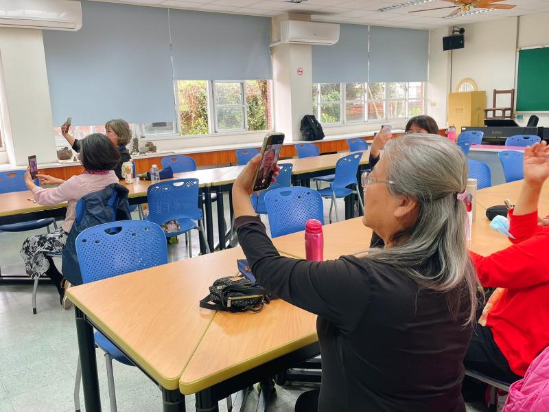 學員神情專注，將手機高高舉起，認真地調整螢幕尋找最完美的角度。