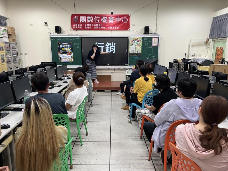 史晴老師站在電子白板前講解「行銷」主題,學員們專注聆聽。