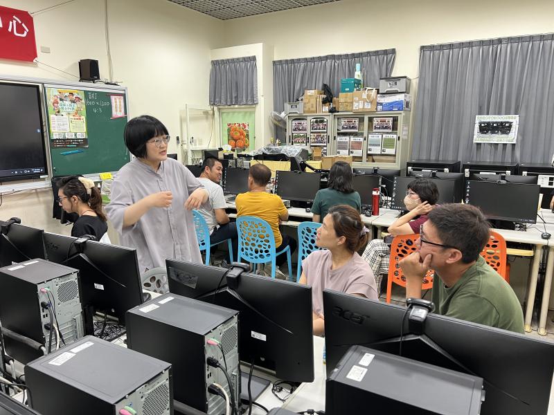 老師站立向學員們講解,學員們圍坐電腦教室認真聆聽討論。