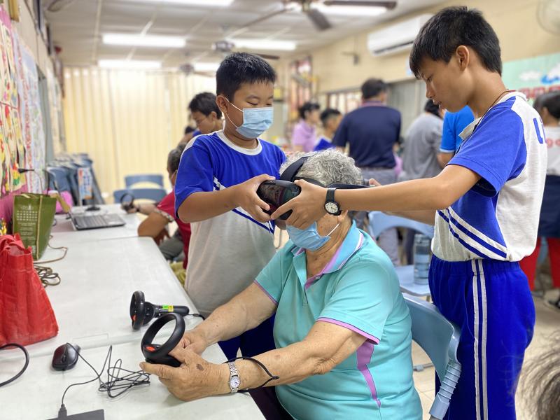 兩位男同學小心翼翼地協助長輩穿戴VR體驗裝置