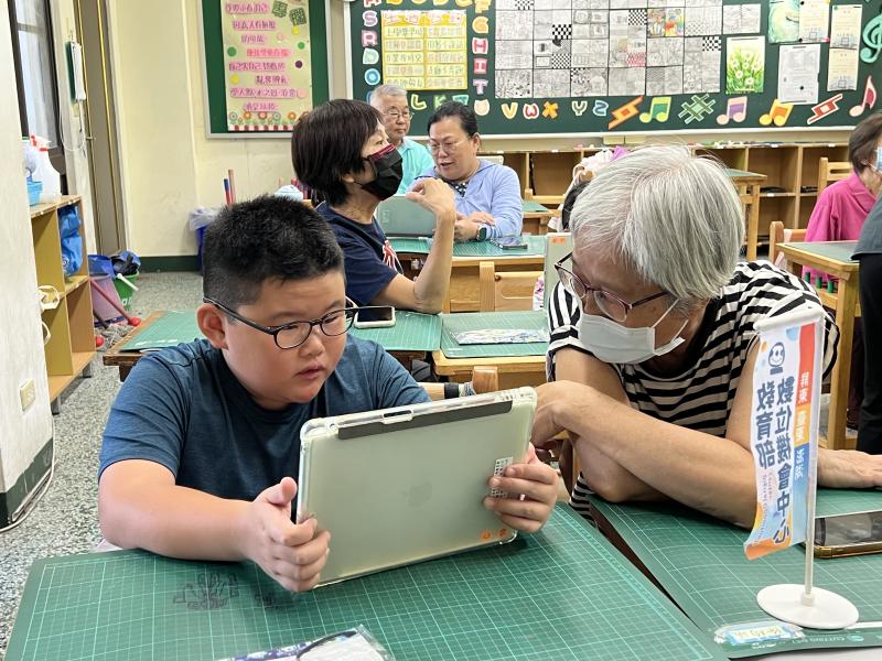 小男童專注地盯著平板上的問答題，一旁的奶奶耐心引導、一起思考答案