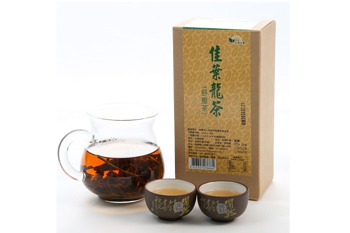 有機佳葉龍茶，玻璃茶壺內盛裝琥珀色的清澈茶葉，倒入兩個小茶杯中飄散出縷縷輕煙。