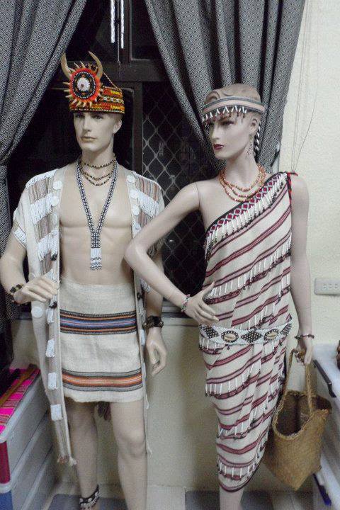 泰雅族的傳統服飾，以多種顏色織成的條紋布料，男性的長衫敞開露胸膛，女性為側肩圍住上胸的連身裙。