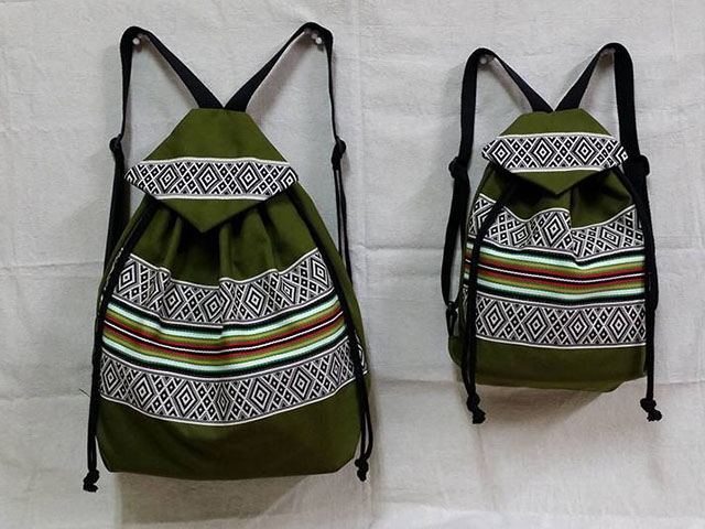 帶有泰雅族圖騰的背包，黑色的背帶，背包以綠色為基底，圖騰與線條以橫條紋交互加疊。