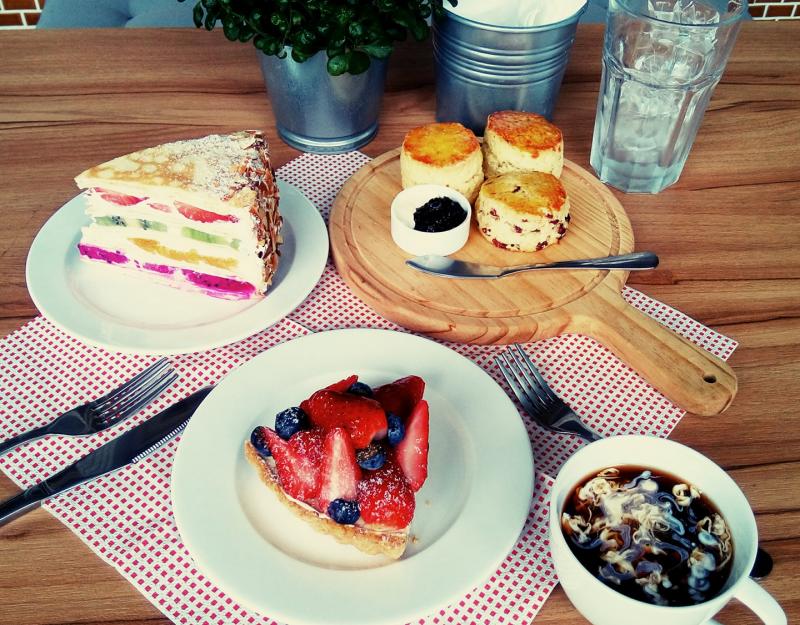 桌上放置著水果千層，另外兩項是放滿草莓的草莓派與檸檬磅蛋糕，以及加滿奶精的咖啡。