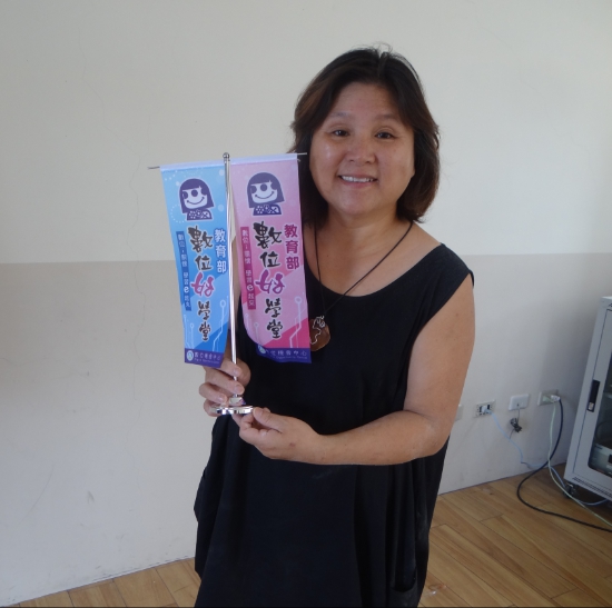 圖為羅秀美老師，拿著數位好學堂的剪影花䋈照。