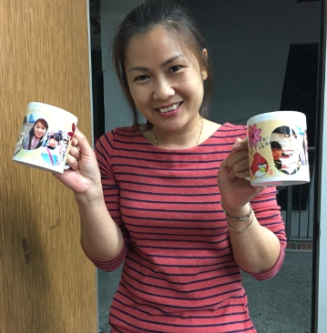 新移民學員開心與印有自己照片的馬克杯合影