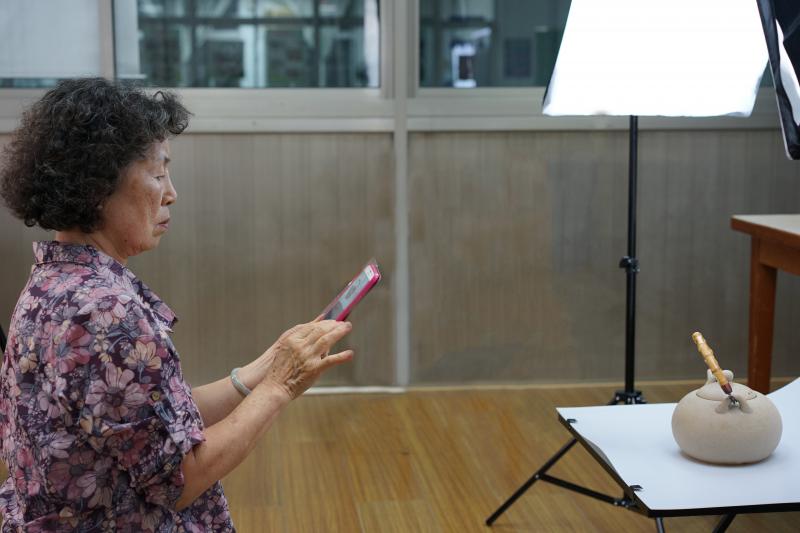 在竹山DOC今年首度開設的「自拍敘事─說出生活中的故事」課程中，DOC學員簡雪正專心地練習使用攝影台燈光補抓茶壼最佳角度。