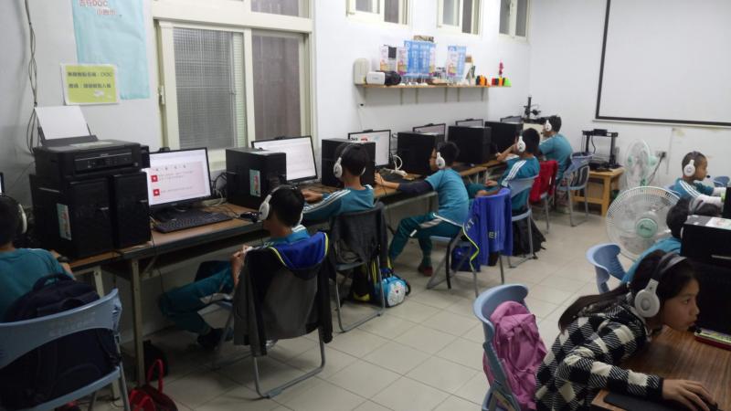 小學生進到教室，坐在電腦桌前將耳機戴上，開始數位學伴的課程。