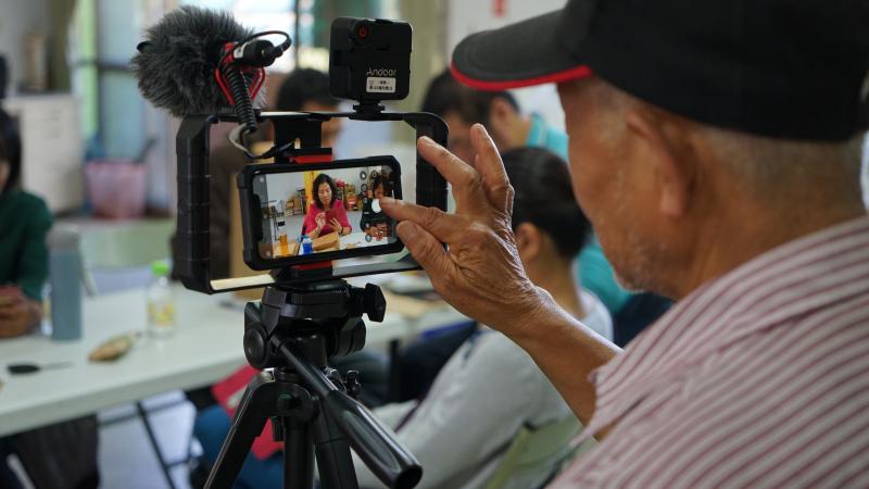 82歲的信義DOC學員鄧平炮在DOC學習使用穩定器攝影後，增加使用手機攝影的信心，現在是錄製學員上課的最好幫手。