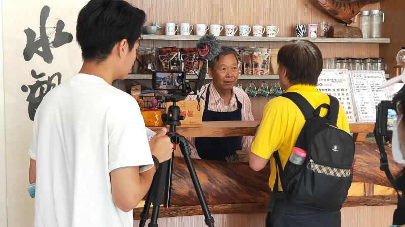 拍攝地點：玉品田咖啡
參與手機微電影課程的三灣DOC學員分別飾演咖啡店的老闆賣咖啡，另一位學員則飾演外地的旅客。講師於一旁拍攝學員演出的畫面。