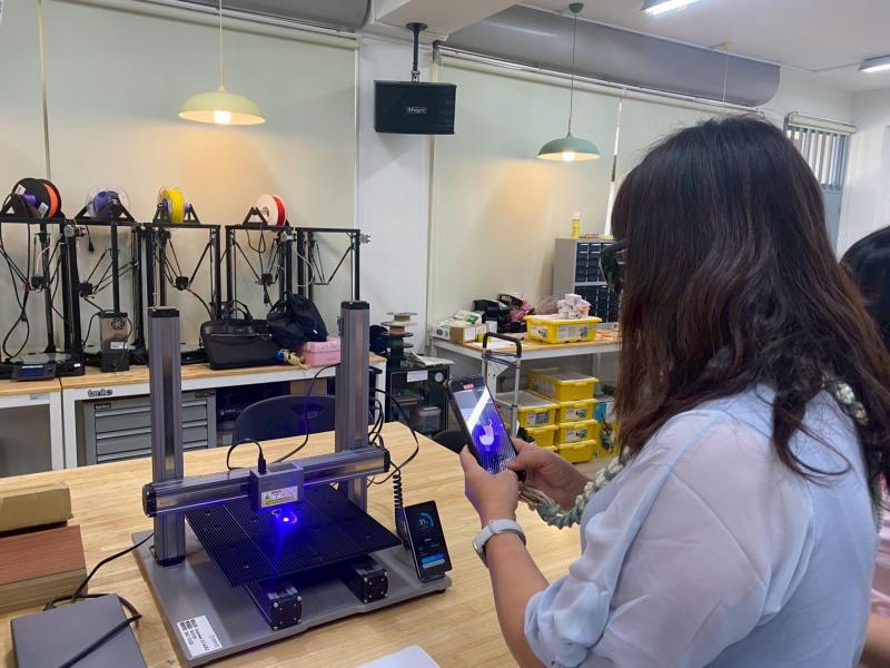 學員們親自操作雷雕機器，並利用手機拍攝雕刻過程來保存留念。