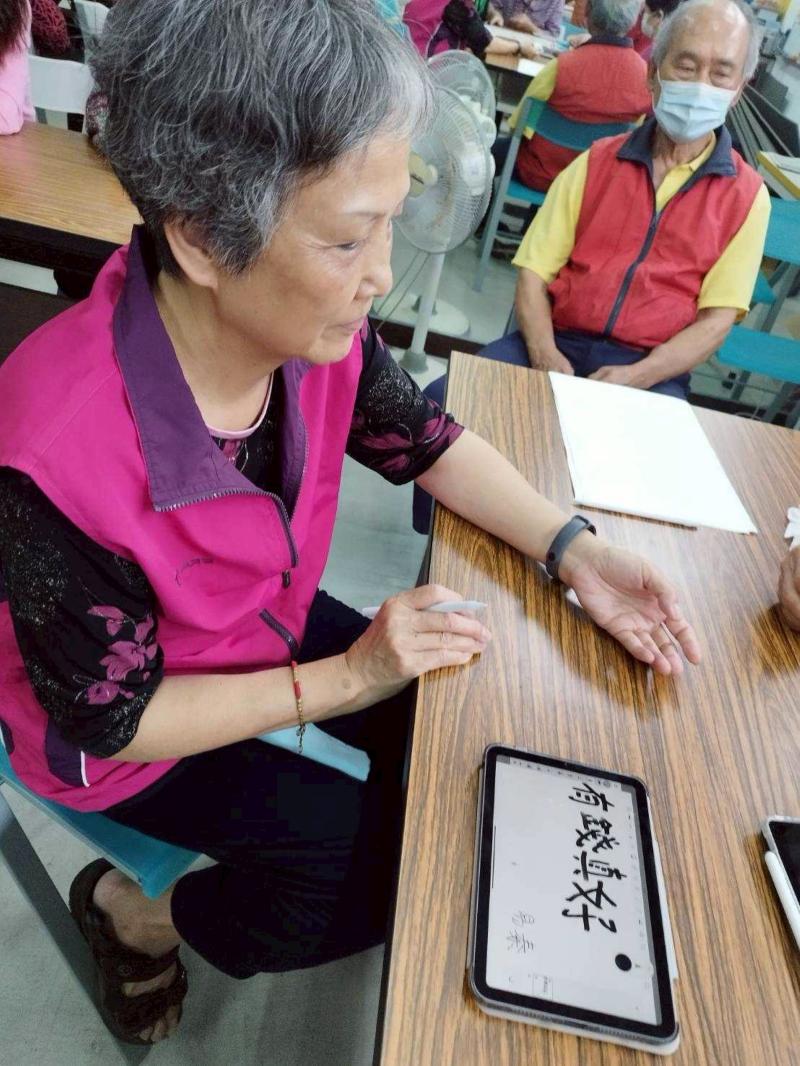 長輩正透過書法來創作電繡的手稿。