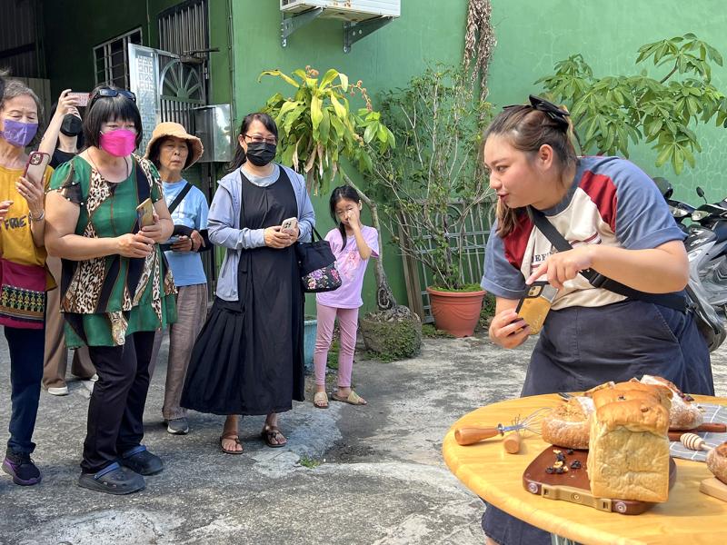 講師以手機示範烘焙產品的拍攝角度，學員在一旁專注觀摩，認真學習拍攝技巧。