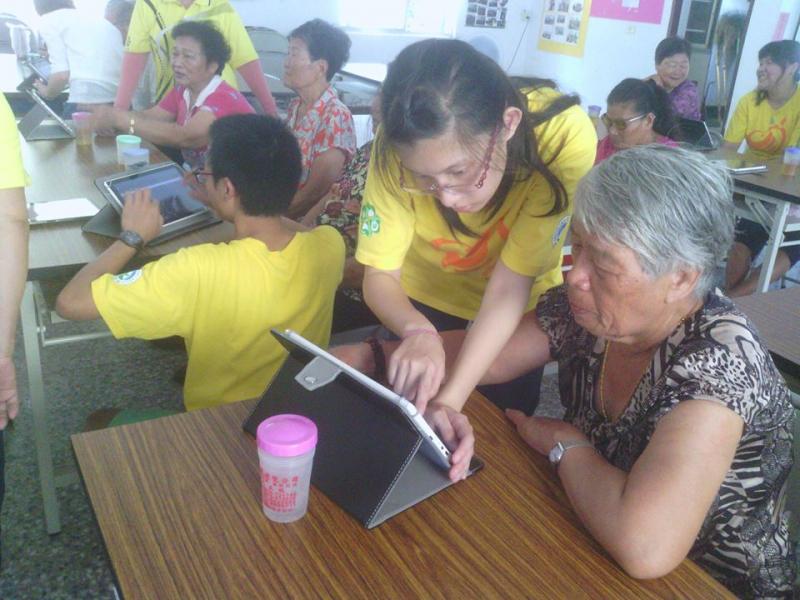 志工協助長輩操作平板。