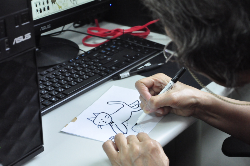 講師指導學員使用電腦搜尋網路圖案，並參考喜歡的圖案手繪自己的絹印設計。