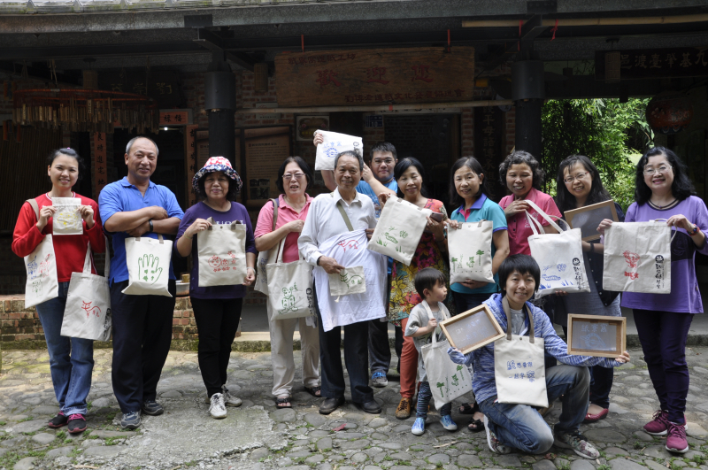 學員拿著印製自己絹印設計的布包開心合影。