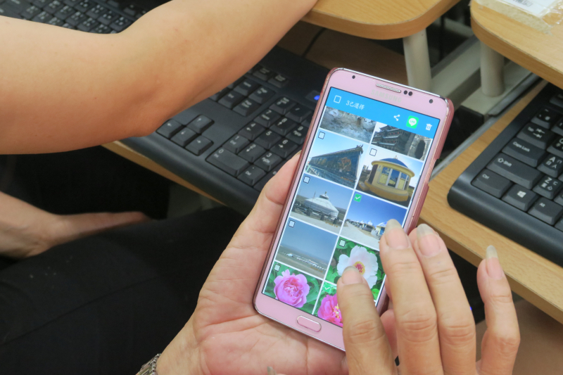 學員正瀏覽手機拍攝照片，從中挑選適合的圖像。