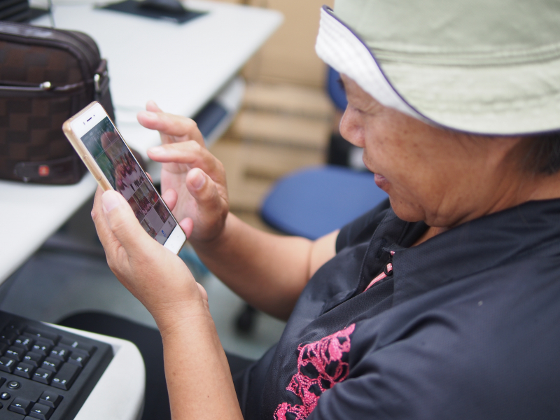 咖啡商家老闆娘正從手機挑選、匯入照片。