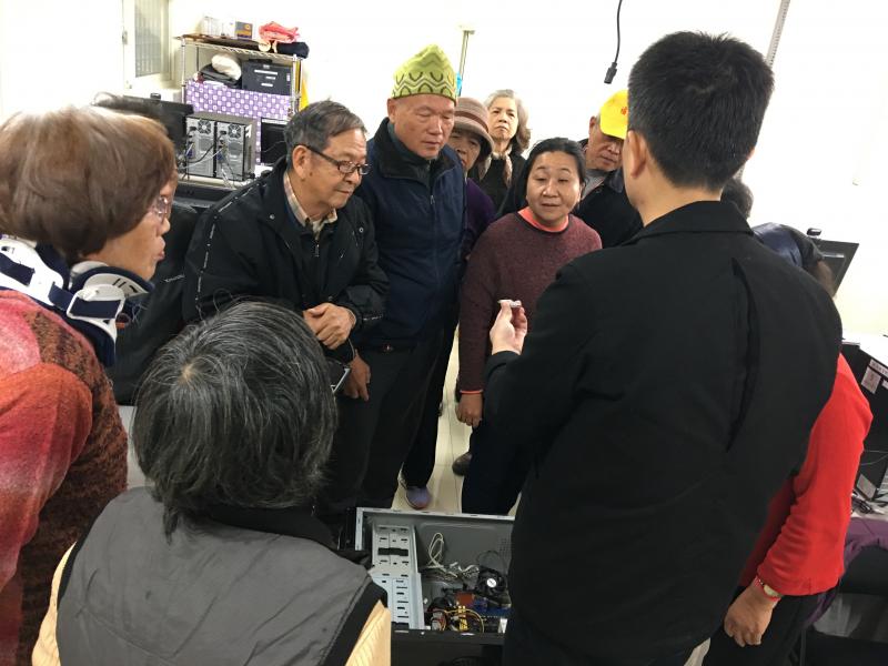 學員圍著老師介紹電腦設備