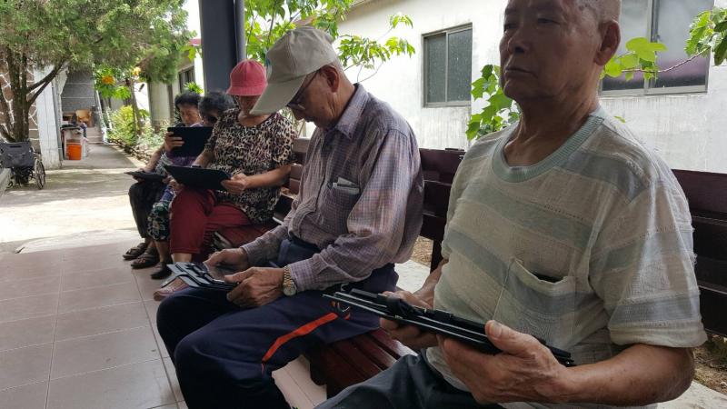 阿公拿著平板，很認真地上課