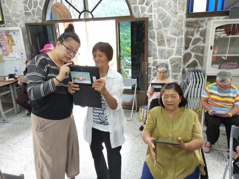 講師與阿嬤正在探索平板的功能，阿嬤認真的神情，真叫人不禁豎起大拇指。