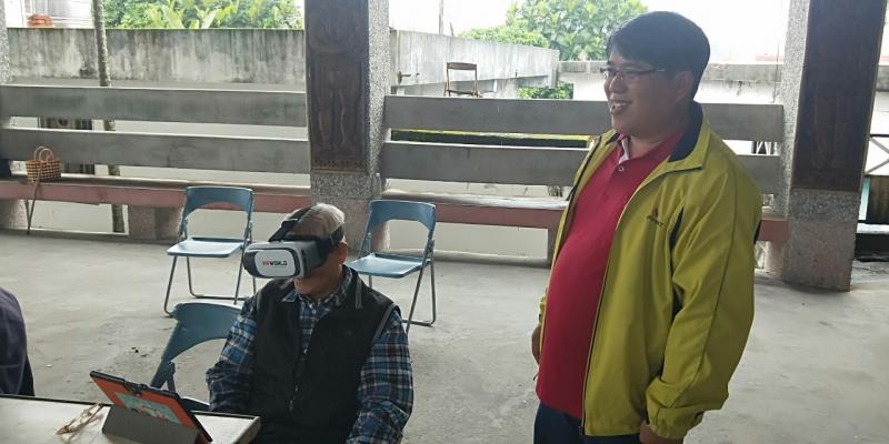 長輩們將VR眼鏡戴在頭上，體驗遊玩VR的遊戲，看到長輩們可愛的反應，講師不禁笑了一下。
