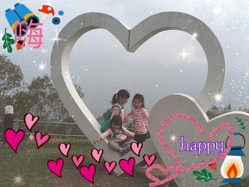 明信片製作，三位小朋友在巨大的空心愛心圖型中坐著，下方有許多藉由電腦合成的愛心圖案與happy字樣。